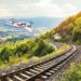 Airplane flying over train tracks, European landscape.