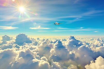 Airplane soaring above clouds towards a distant horizon.