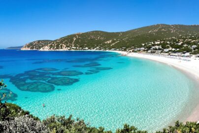 Crystal blue waters lapping against a sun-drenched Greek island beach.