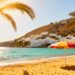 Sunny Spanish beach with palm trees and white buildings.