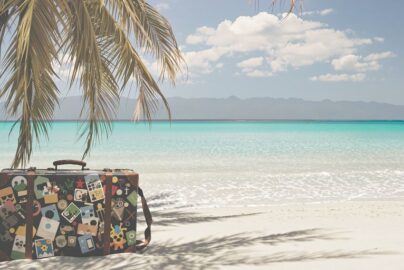 Beach with suitcase and distant mountains.