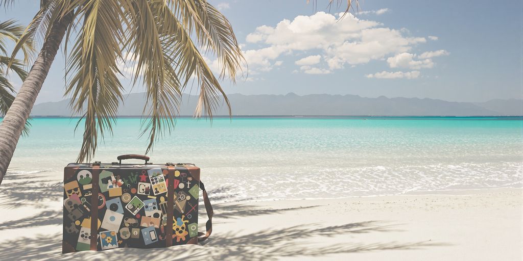 Beach with suitcase and distant mountains.