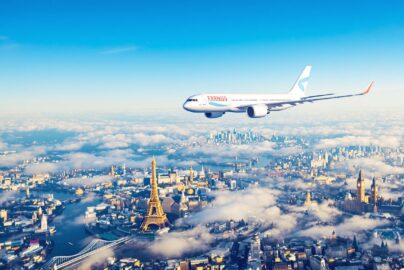 Airplane flying over European landmarks on clear sunny day