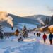 Snowy village with cabins and travelers in winter.