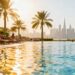 Dubai resort pool with palm trees and skyscrapers.