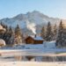 Snowy mountain cabin with frozen lake in winter.