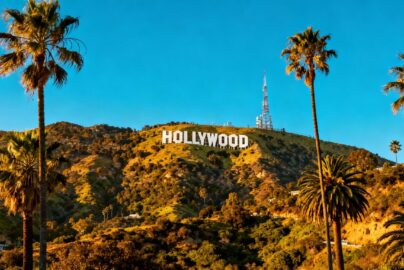 Hollywood sign with palm trees and sunny sky.